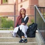 First generation student sitting on campus stairs